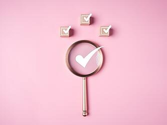 magnifying glass with white ticks against pink background